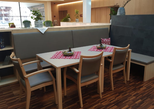 Sitzgruppe aus Holztischen und Stühlen in Sozialzentrum Sölden
